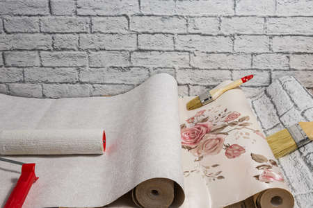 Rolled rolls of wallpaper, a brush and a roller are prepared for apartment renovation. Home...