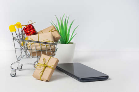 Online shopping symbols: cart with packages, gifts and smartphone. Online shopping concept.の写真素材