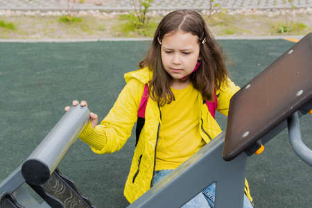 9 year old girl schoolgirl is engaged in fitness on the outdoor simulator.