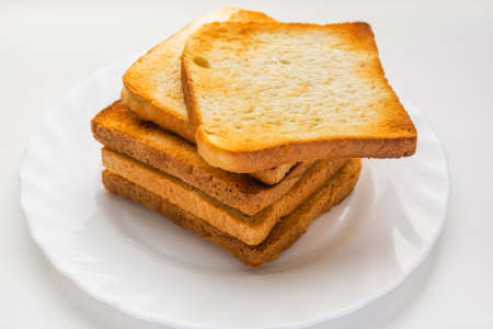 Several toasted slices of white bread are prepared for breakfast. Crispy toast is spread on a plateの写真素材