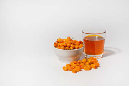 Oil and berries of sea buckthorn on a white background. The concept of making medicinal oil.