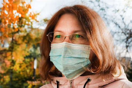 Close-up portrait of a 40-year-old woman wearing glasses wearing a medical mask.の写真素材