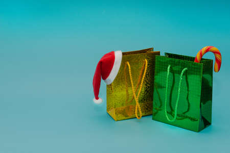 Two packages with gifts, Santa Claus hat and candy cane on a blue background. Holiday gifts shopping...