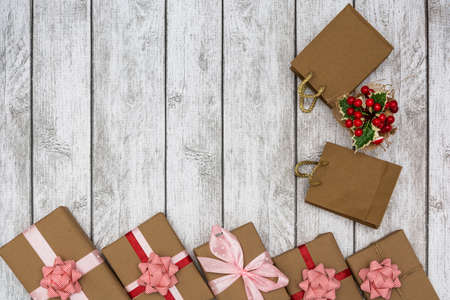 Holiday gifts wrapped in brown paper and holly on a white wooden background. New Year and Christmas concept. Flat lay.の写真素材