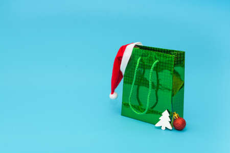 Green bag with gifts and Santa Claus hat for Christmas or New Year. Holiday gifts shopping concept.の写真素材