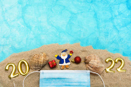 Christmas decorations, seashells, a medical mask on the sand. The concept of celebrating New Year...