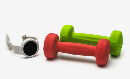 Smart wrist watch and dumbbells on a white isolated background. Health control concept with smart watch in fitness class.の写真素材