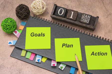 Gray weekly planner with bookmarks and stickers on a brown background. On yellow stickers it is...
