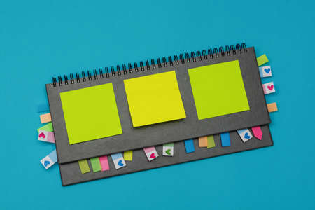 Gray weekly planner with bookmarks and yellow stickers on a light blue background. Business planning and personal growth concept. Flat lay. Copy space.の写真素材