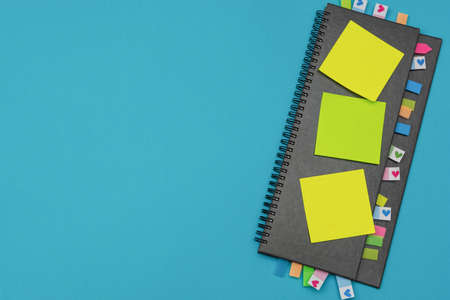 Gray weekly planner with bookmarks and yellow stickers on a light blue background. Business planning...