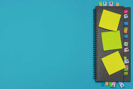 Gray weekly planner with bookmarks and yellow stickers on a light blue background. Business planning and personal growth concept. Flat lay. Copy spaceの写真素材
