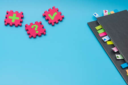 Gray weekly planner with bookmarks and puzzles with symbols on a blue background. The concept of planning and solving complex problems for the development of business and personalityの写真素材