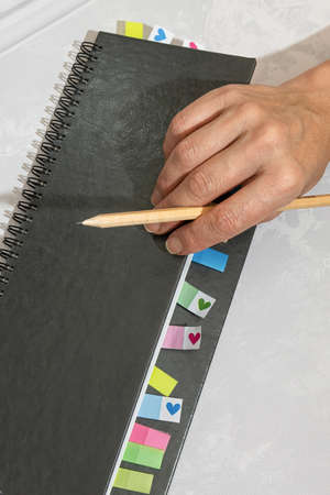 A woman holds a gray diary with bookmarks in her hands. Business planning concept for development