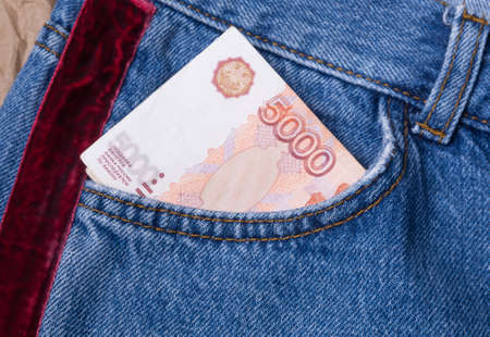 A Russian banknote of 5000 rubles sticks out of the front pocket of jeans. Written in Russian - a fake ticket of the Bank of Russia is punishable by law.の写真素材