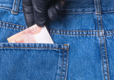 From the back pocket of jeans, the thief pulls out a Russian banknote of 5000 rubles