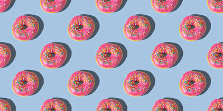 Repeating pattern of pink donuts on a blue background. flat lay.の写真素材