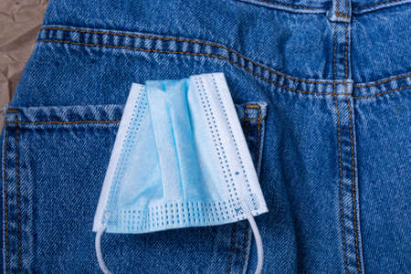 A used medical mask sticks out of the back pocket of his jeans. Coronavirus concept.