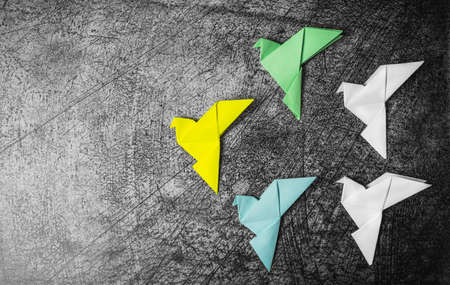 On a gray textured background, several multi-colored, paper doves, made in the origami technique. The concept of peace after the war.の写真素材