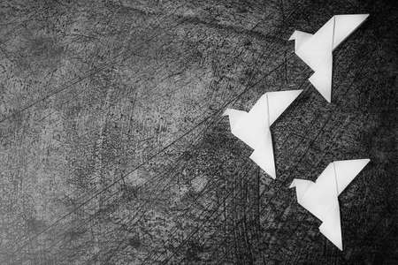 On a gray texture background, there are three white paper doves made in the origami technique. The concept of peace after the war.の写真素材