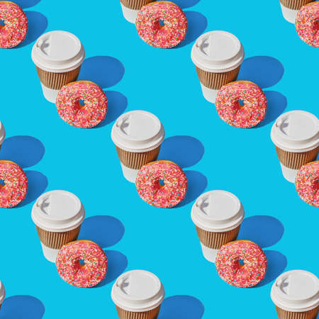 A repeating pattern of a cup of coffee and a red donut on a blue background.の写真素材