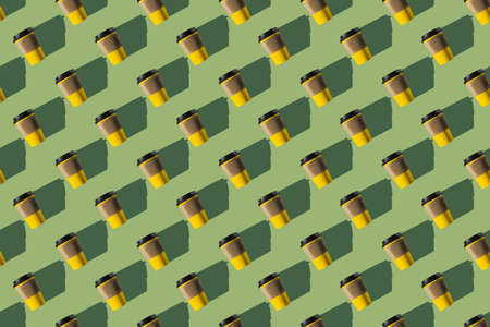 Pattern of yellow paper coffee cups on a green background. flat lay.の写真素材