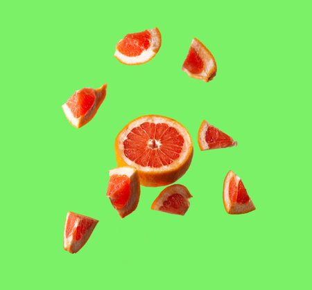 Isolated flying fresh grapefruit slices. Fresh grapefruit on green background.