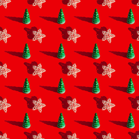 A repeating pattern of a star and a toy Christmas tree on a red background. New year and christmas concept.の写真素材