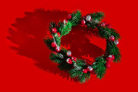 Christmas fir and holly wreath with shadow on red background. christmas concept.の写真素材
