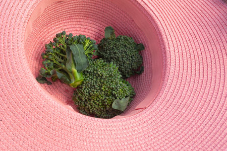Three green broccoli florets are in a pink gardener's hat. gardening concept.の写真素材