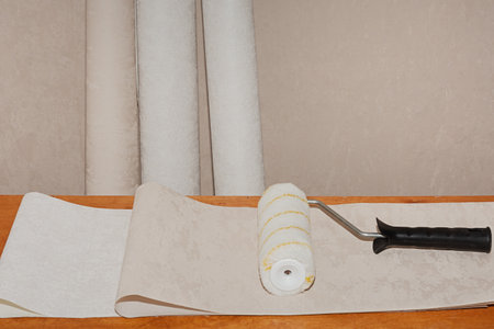 Textured pastel wallpaper, roller and glue ready to renovate a room.の写真素材