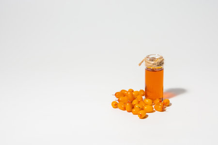 A bottle of sea buckthorn oil and sea buckthorn berries on a white background.