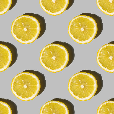 Uniform pattern of lemon slices with shadow on a gray background. Flat layout.