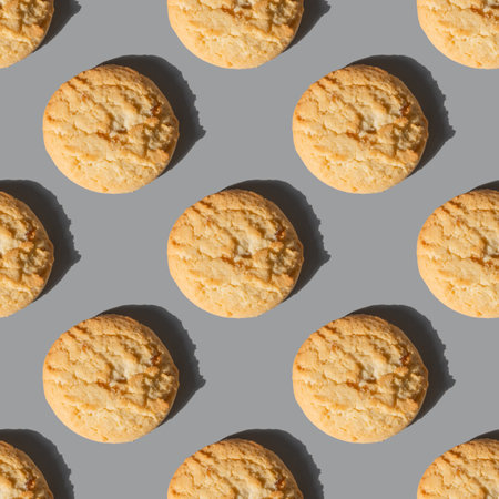 Seamless pattern of fresh shortbread cookies with sharp shadow on gray background.