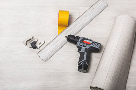 On the floor is a roll of linoleum, a baseboard and a screwdriver. Construction materials and a set of tools for laying linoleum. The concept of covering the floor with linoleum.の写真素材