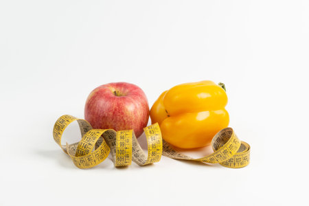 Diet food with fresh fruits and vegetables and measuring tape on white background. Weight loss and...