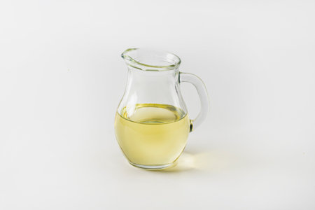 A jug filled with clear vegetable oil stands on a white background.の写真素材