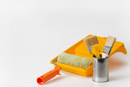 Brushes for home or apartment renovation, yellow dandelions, roller, paint tray make up an elegant composition on a white background. Spring and summer renovation concept. Copy space.の写真素材