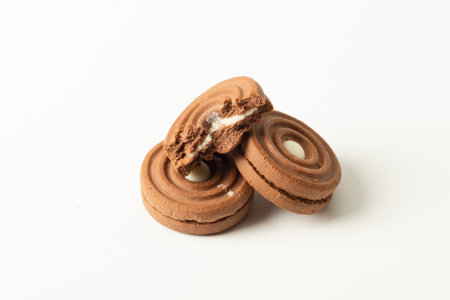Three chocolate cookies with icing filling on white background.の写真素材