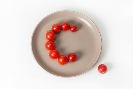 A group of cherry tomatoes lie on a gray plate in the shape of the letter C. Tomatoes contain a lot...