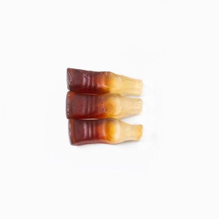 Three chewy soda bottle-shaped candies on a white background. Top view. Isolated.の写真素材