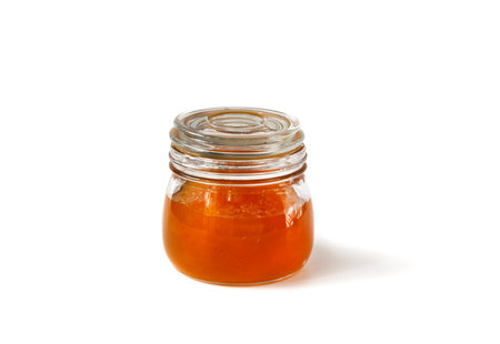 Sweet pumpkin-orange marmalade or confiture in a small jar on a white background. Isolated. Golden pumpkin jam.の写真素材