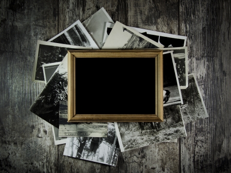 Photo frame with lots of photos lying on an old table.