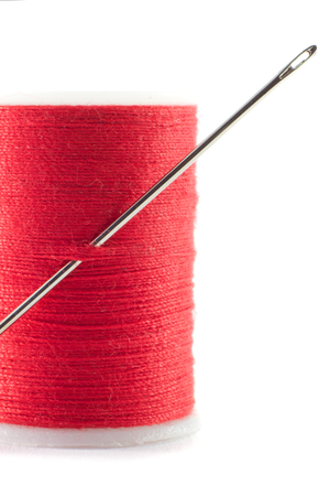 A needle and red cotton isolated on a white background.の写真素材