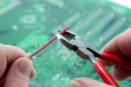 Technician repairing an electronic circuit board with cutters.の写真素材