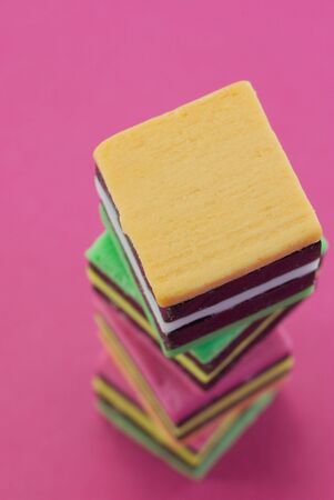 A stack of colorful liquorice allsorts on a pink background.のeditorial素材