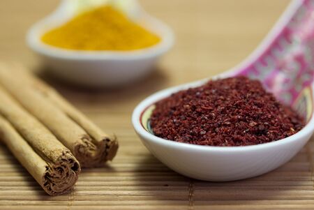 Two Asian style spoons and cinnamon sticks on a bamboo mat.の写真素材