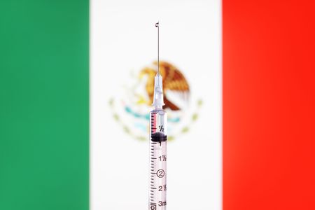 A needle and syringe on a mexican flag background.の写真素材