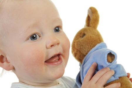 A baby boy and his toy rabbit, isolated on a white background.