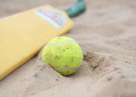 A beach cricket bat with tennis ball on the sand.の写真素材