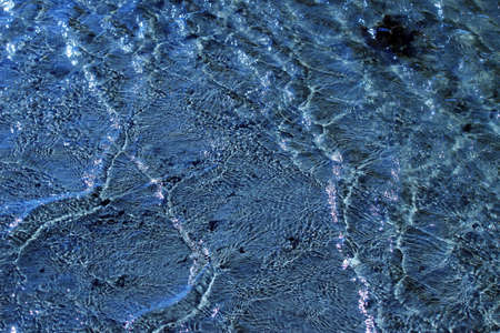 Blue water ripples and swirls and creates shadows, can be used as a background 